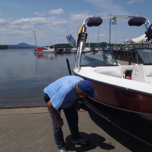 A man inspects his boat for aquatic invasive species